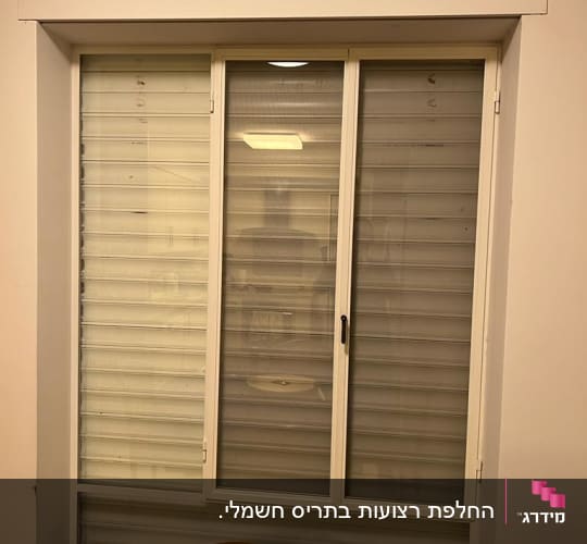 תריסים סגורים על חלון עם מסגרת לבנה